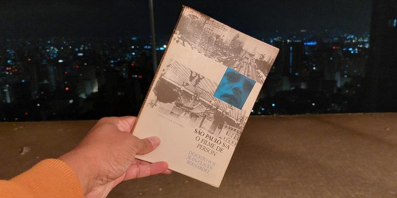 O livro “São Paulo S/A – O filme de Person descrito por Jean-Claude Bernardet” e a vista da cidade pela janela do Copan